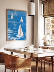 Three sailboats on textured blue water, illustrative style nautical wall art print with cream sails, in a styled room mockup
