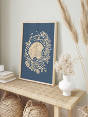Ornate scallop shell illustration with beige botanical swirls on a deep blue background, in an alternate framed mockup