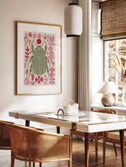 Olive green scarab beetle print with white stripes, surrounded by red abstract botanical shapes and, in a styled room mockup