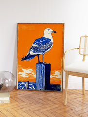 Seagull Wall Art linocut print featuring a blue and white seagull on a dark blue wooden post against an orange sky and ocean. - Image 2
