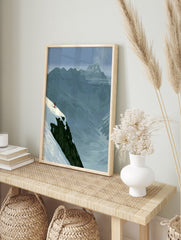 Minimalist illustration of a skier on a snowy mountain cliff edge, blue mountain background, in an alternate framed mockup