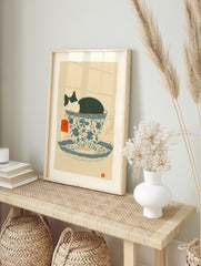 Whimsical cat art print showing a black and white cat sleeping soundly inside a blue and white patterned teacup. - Image 3