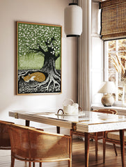 Woodcut style print of a sleeping russet fox curled at the base of a large tree with green leaves, in a styled room mockup