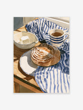 Watercolor still life painting of a loaf of bread, coffee, and butter on a blue and white striped cloth