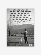 Monochrome print of a man and dog in a field looking up at pixelated Space Invaders in the sky, with 'LIFE' logo