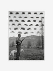 Monochrome print of a man with a rifle and dog looking at pixelated Space Invaders in the sky