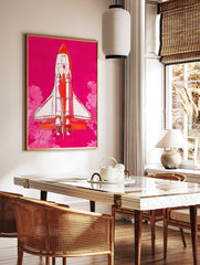 Illustrative Space Shuttle rocket in white and orange against a vibrant pink sky with pink clouds, in a styled room mockup