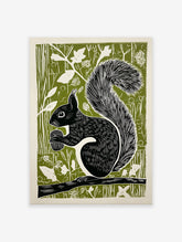 Black squirrel linocut art print on a green background, holding an acorn while sitting on a branch, woodland animal decor.