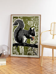 Black and white linocut art print of a squirrel holding an acorn on a branch against an olive green forest background. - Image 2