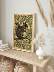 Woodcut style print of a squirrel on an oak branch, surrounded by green leaves and acorns on, in an alternate framed mockup