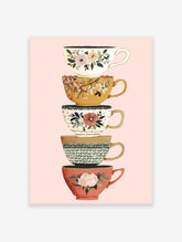 Stacked teacup wall art print featuring five colorful cups with floral and botanical designs on a light pink background.