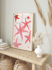 Pink starfish illustration art print with small stars on a neutral background, in an alternate framed mockup