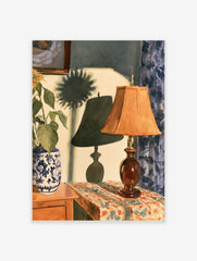 Watercolor painting of a lamp and sunflower vase on a table with blue curtains and a prominent shadow on the wall
