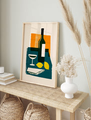 Modern still life wall art with wine bottle, cocktail glass, and lemons on a teal table, in an alternate framed mockup