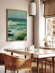 Painting of stormy green sea with a large white wave crashing on rocks and yellow flowers, in a styled room mockup