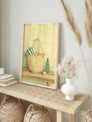 Illustrative print of a straw market bag with a striped towel, green bottle, and spool on a, in an alternate framed mockup