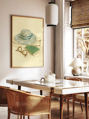 Illustrative print of a blue and white striped straw hat, green book, and eyeglasses on a light, in a styled room mockup