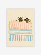 Stack of pink and blue striped towels with round sunglasses on a cream background, coastal poster print