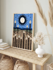 Stylised field art print with white-topped plants, black sun, blue sky, and distant mountains, in an alternate framed mockup