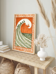 Stylised green and white ocean wave against burnt orange background, within ornate scrollwork, in an alternate framed mockup