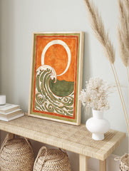 Stylised ocean wave art print with cream and green patterns, orange sky, white sun/moon, and, in an alternate framed mockup