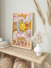 Celestial sun and moon wall art with 'Be Kind & Do Your Thing' text and clouds on a peach background, displayed as the same artwork in an alternate framed wall art mockup
