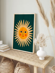 Illustrative sun face wall art print with orange sun and dark teal background, shown in an alternate framed wall art mockup