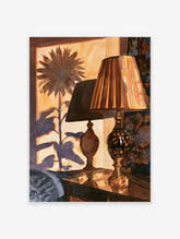 Illustrative wall art print of a table lamp and sunflower silhouette in warm golden tones