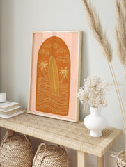 Illustrative surfboard, two palm trees, waves, sun, and clouds in an arched orange design, in an alternate framed mockup
