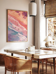 Aerial view poster of three surfers on surfboards in pastel pink and blue ocean waves with sandy beach and palm trees. - Image 2