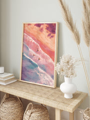 Aerial view poster of three surfers on surfboards in pastel pink and blue ocean waves with sandy beach and palm trees. - Image 4