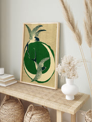 Stylised illustration of two swallows in flight with a green crescent moon on a textured tan, in an alternate framed mockup
