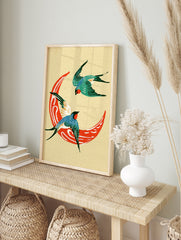 Two swallows flying around a red crescent moon, illustrative style print on cream background, in an alternate framed mockup