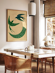 Circular art print of two green swallows in flight with a wave motif on a textured beige background, in a styled room mockup
