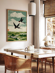 Woodblock style print of two black and white swallows with red throats flying over green rolling, in a styled room mockup
