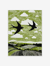 Linocut style print of two black swallows flying over green fields with white clouds