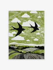 Linocut style print of two black swallows flying over green fields with white clouds