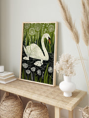 Illustrative print of a white mother swan and three cygnets in dark water, surrounded by, in an alternate framed mockup