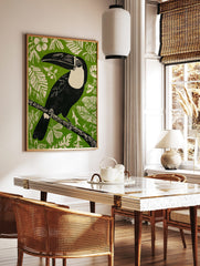 Illustrative black toucan with cream chest and large beak on branch against green background with, in a styled room mockup
