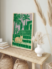 Tropical cat print of a striped feline resting on steps with palm trees and a building against a purple sky. - Image 3