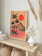 Illustrative tropical island print with palm trees, mountains, red sun, and pink water on tan, in an alternate framed mockup