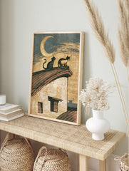 Vintage illustration of two cats sitting on a roof under a crescent moon, paper wall art print, in an alternate framed mockup