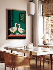 Two white geese with red beaks facing each other over cake slices on a table, against a teal green, in a styled room mockup