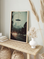 Retro photographic print of a flying saucer hovering over a hazy city street with car, in an alternate framed mockup