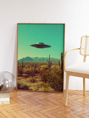 Retro UFO wall art print featuring a flying saucer hovering over a desert landscape with cacti and mountains under a teal sky. - Image 2