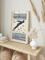 Illustrative print of an underwater swimmer in a dark blue suit and flippers, surrounded by, in an alternate framed mockup