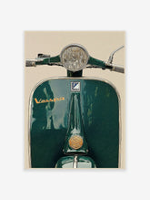 Close-up front view of a dark green vintage Vespa scooter with chrome headlight and 'Vespa' script logo