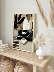 Modern illustrative wall art of a person with a vinyl record player, coffee, and plant, in an alternate framed mockup