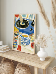 Illustrative art print of a hand on a vinyl record player with tea and a stack of records in, in an alternate framed mockup