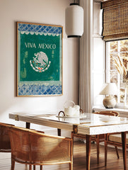 VIVA MEXICO wall art with white text and Mexican eagle emblem on dark green, framed by blue, in a styled room mockup